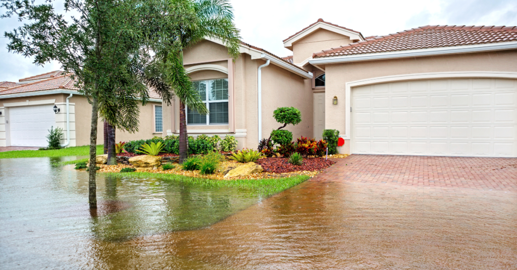 Residential home with high floodwaters surrounding the street and the home's foundation after a hurricane.